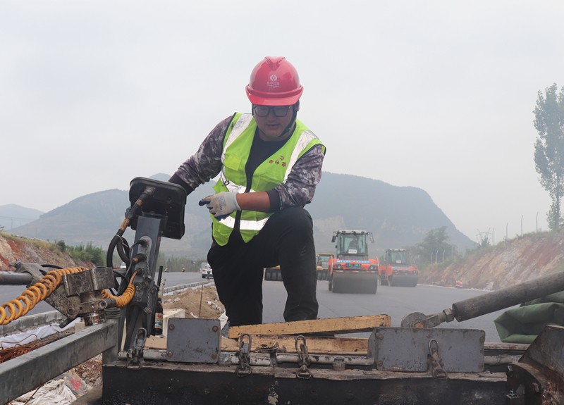 4、油層施工隊(duì)長(zhǎng)朱紹濤根據(jù)現(xiàn)場(chǎng)實(shí)際微調(diào)攤鋪機(jī)控制攤鋪質(zhì)量_副本